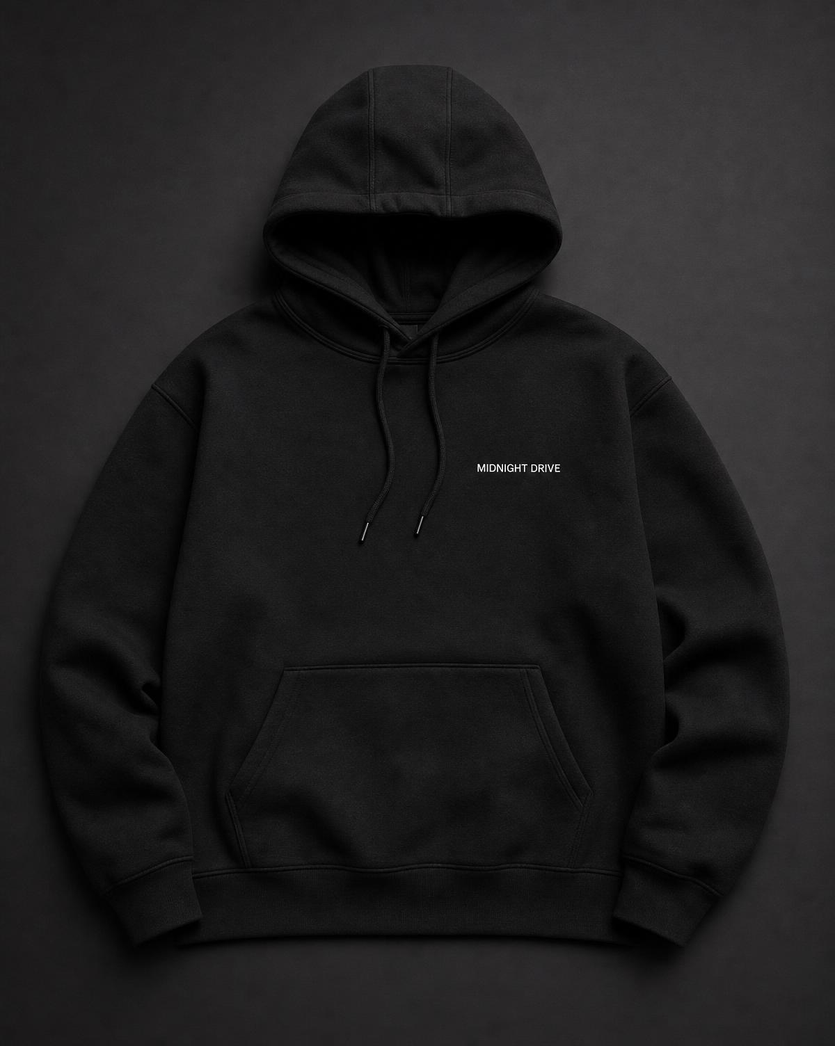 Heavyweight black automotive hoodie photographed in a low-lit garage
